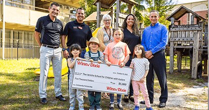 Group of Southeastern Grocers associates standing next to teachers from The Jericho School for Children with Autism. In front of them are young students holding a big $5,000 check.