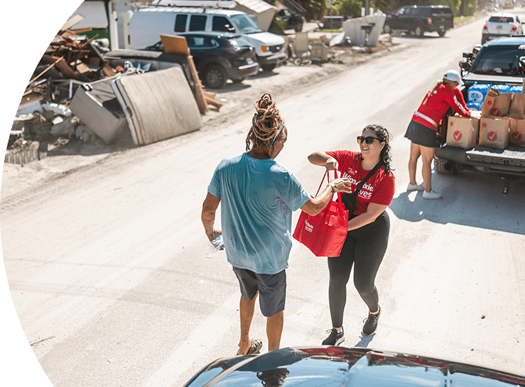 Winn-Dixie employee handing a bag of donation items to a hurricane victim
