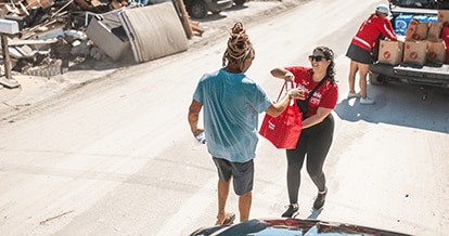 Winn-Dixie employee handing a bag of donation items to a hurricane victim