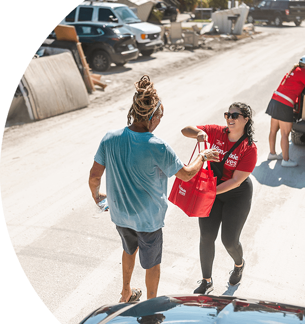 Winn-Dixie employee handing a bag of donation items to a hurricane victim