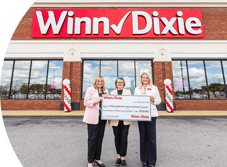 Southeastern grocers teams leaders standing in front of a Winn-Dixie store. They are holding a $350,000 check to Making Strides Against Breast Cancer.