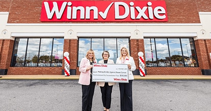 Southeastern grocers teams leaders standing in front of a Winn-Dixie store. They are holding a $350,000 check to Making Strides Against Breast Cancer.