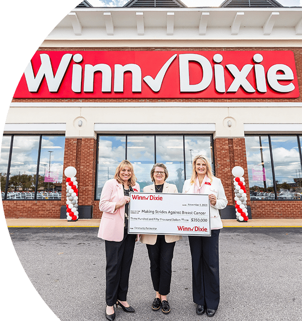 Southeastern grocers teams leaders standing in front of a Winn-Dixie store. They are holding a $350,000 check to Making Strides Against Breast Cancer.