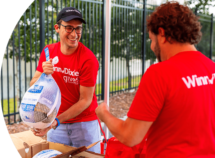 Winn-Dixie gives foundation volunteer holding a frozen turkey.