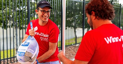 Winn-Dixie gives foundation volunteer holding a frozen turkey.