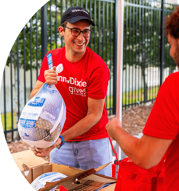 Winn-Dixie gives foundation volunteer holding a frozen turkey.