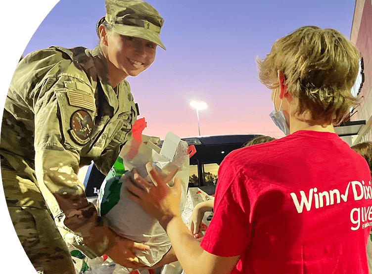 Winn-Dixie gives foundation volunteer helping military service member with placing groceries in car.