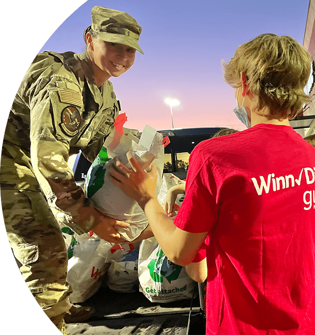 Winn-Dixie gives foundation volunteer helping military service member with placing groceries in car.