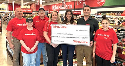 Group of Winn-Dixie employees inside of a store holding a check for the American Heart Association