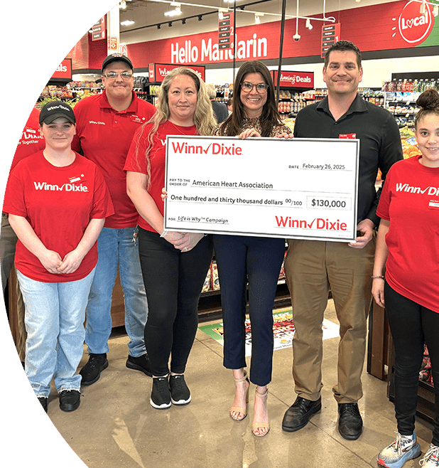 Group of Winn-Dixie employees inside of a store holding a check for the American Heart Association