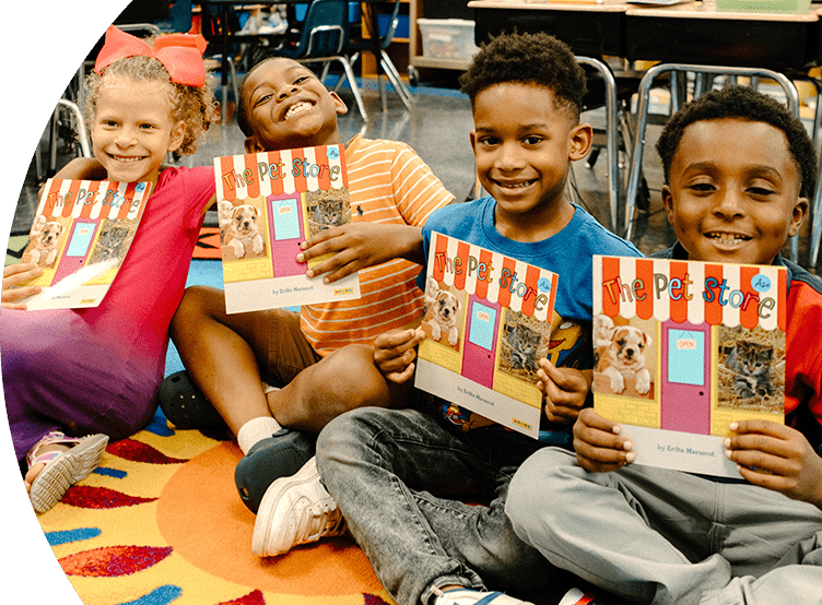 Kids smiling in a classroom holding books