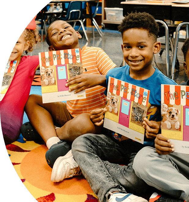 Kids smiling in a classroom holding books