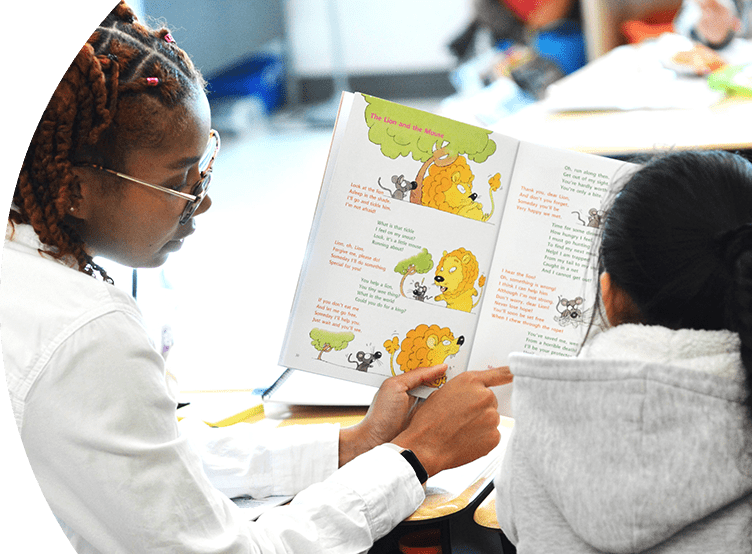 Two young girls reading a book.