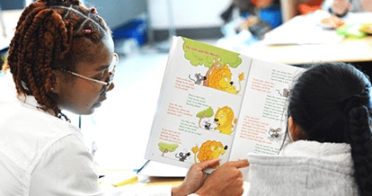Two young girls reading a book.