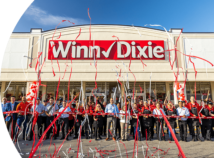 Grand opening photo of Winn-Dixie in Miami. A group of employees out front of store looking excited with confetti. 