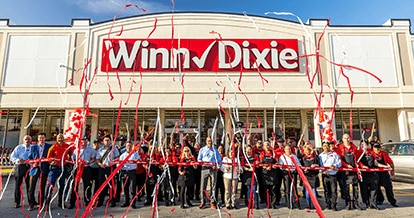 Grand opening photo of Winn-Dixie in Miami. A group of employees out front of store looking excited with confetti. 