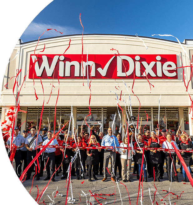 Grand opening photo of Winn-Dixie in Miami. A group of employees out front of store looking excited with confetti. 
