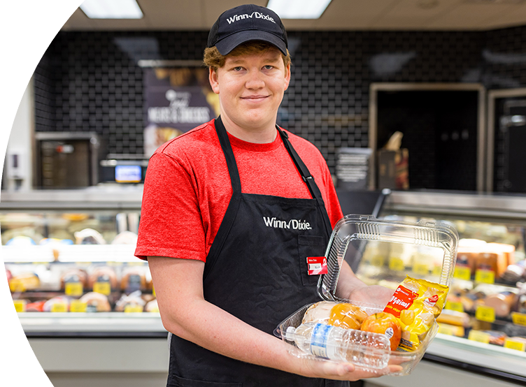 Winn-Dixie Associate holding a to-go-container filled with food.