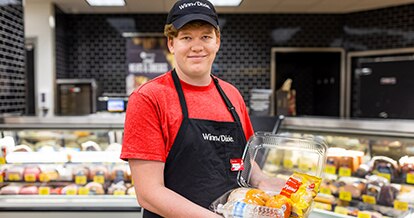 Winn-Dixie Associate holding a to-go-container filled with food.