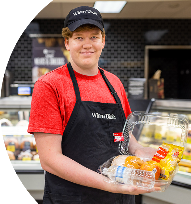 Winn-Dixie Associate holding a to-go-container filled with food.