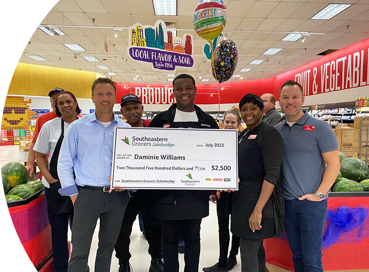 Group of Winn-Dixie employees smiling while one holds a big check.