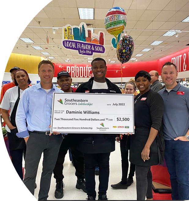 Group of Winn-Dixie employees smiling while one holds a big check.