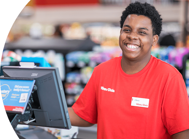 Smiling Winn-Dixie cashier standing behind the cash register machine.