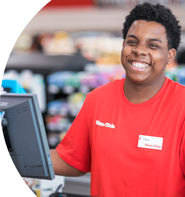 Smiling Winn-Dixie cashier standing behind the cash register machine.