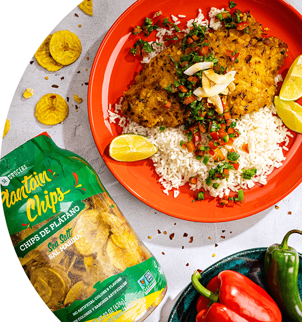 Plantain-crusted cod with coconut rice served on a plate. Next to the plate, there is a container of SE Grocers plantain chips.