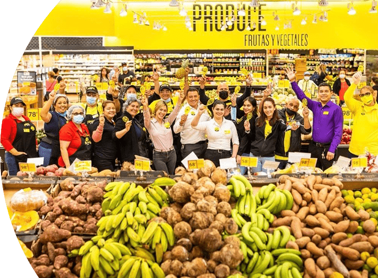 Group of Fresco y Más employees gathered at the produce section while cheerfully holding up yellow maracas.