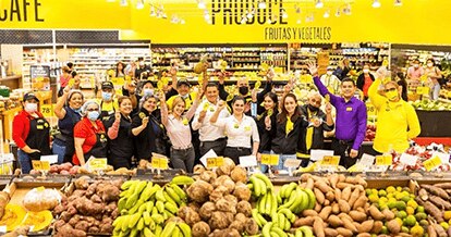 Group of Fresco y Más employees gathered at the produce section while cheerfully holding up yellow maracas.