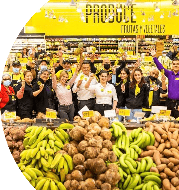Group of Fresco y Más employees gathered at the produce section while cheerfully holding up yellow maracas.