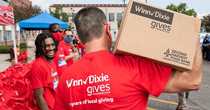 Winn-Dixie Gives Foundation volunteer carrying a box with donations.