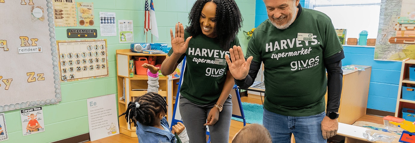 Two gives Foundation volunteers high-fiving a young girl.