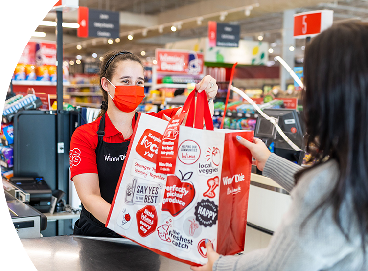Winn-Dixie cashier handing reusable grocery bag to shopper