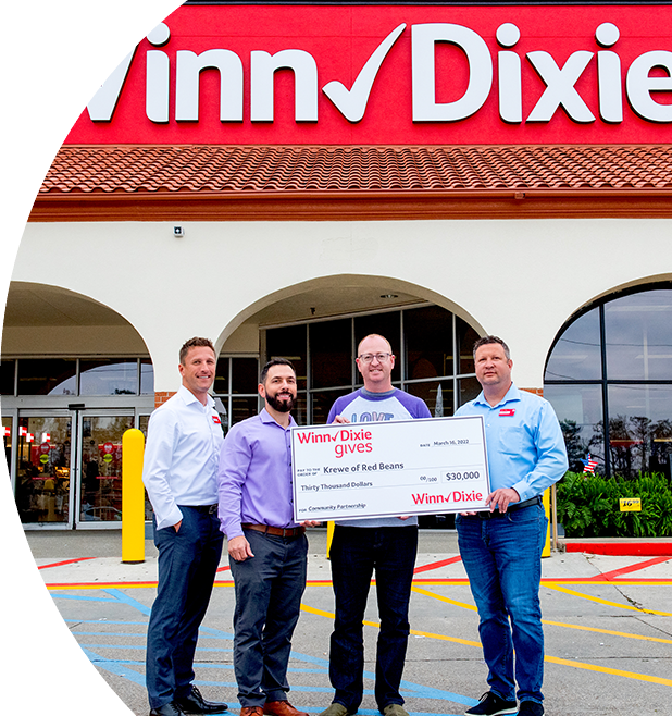 Group of people in front of a Winn-Dixie store holding a big check