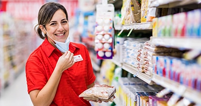 Winn-Dixie associate smiling and holding brown sugar bags in front of the sugar aisle