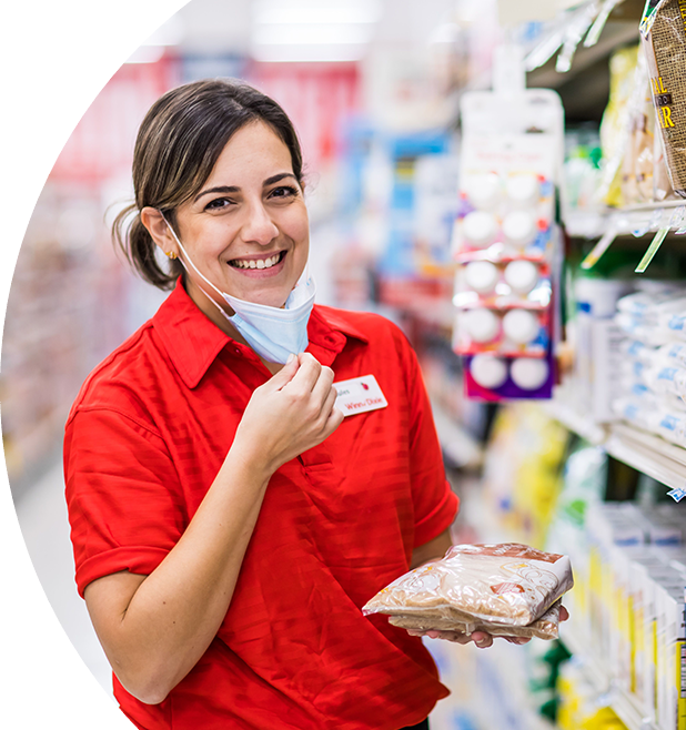 Winn-Dixie associate smiling and holding brown sugar bags in front of the sugar aisle